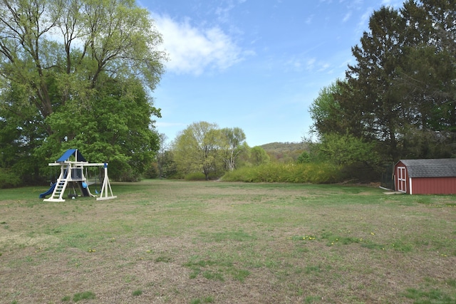 view of yard with an outdoor structure, a playground, and a storage shed