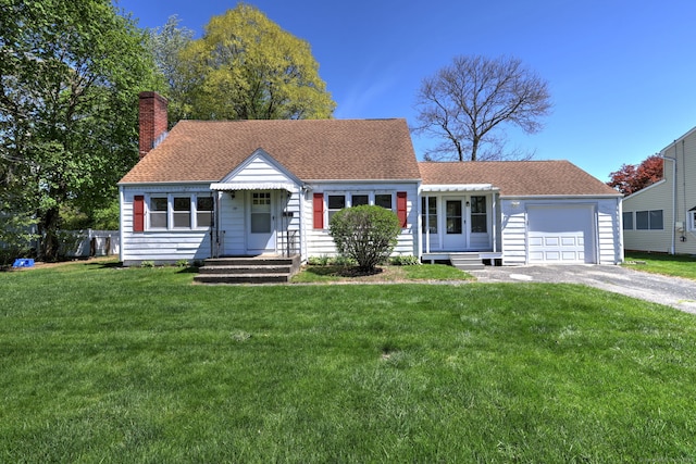 view of front of home featuring aphalt driveway, an attached garage, a front yard, a chimney, and a shingled roof