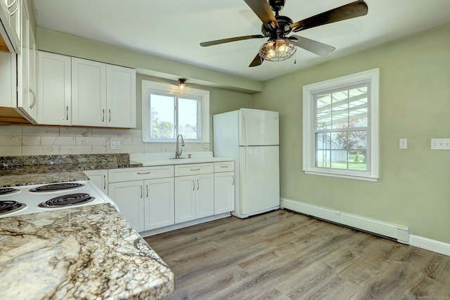 kitchen with freestanding refrigerator, a healthy amount of sunlight, tasteful backsplash, and a baseboard heating unit