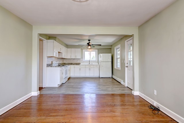 kitchen with a sink, white cabinetry, baseboards, ceiling fan, and white appliances