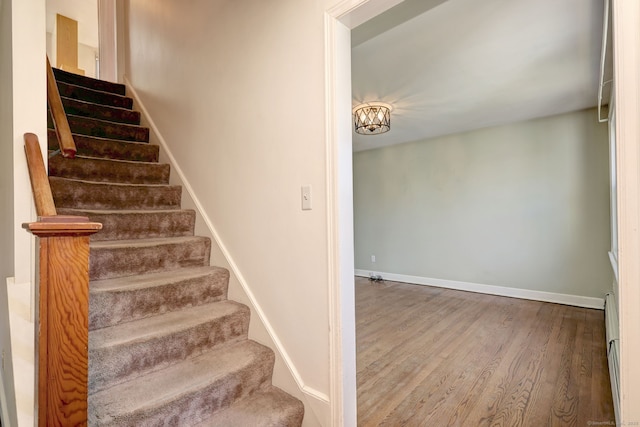 stairs featuring baseboards, a baseboard radiator, and wood finished floors