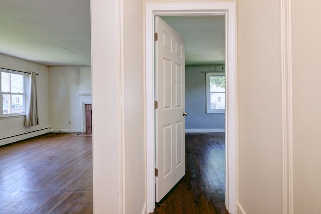 corridor with baseboards, dark wood-style floors, plenty of natural light, and a baseboard heating unit