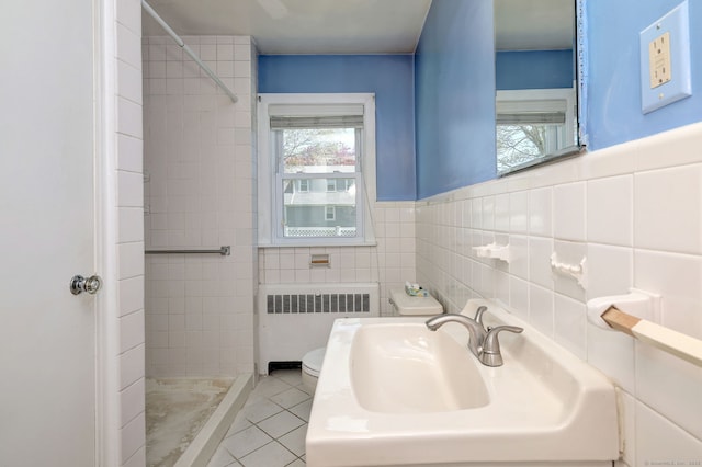 bathroom featuring a sink, tile walls, toilet, radiator heating unit, and a shower stall
