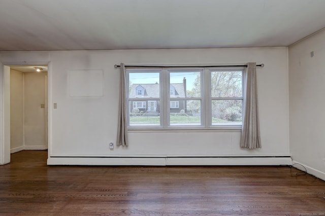 empty room featuring a baseboard heating unit, baseboards, and wood finished floors