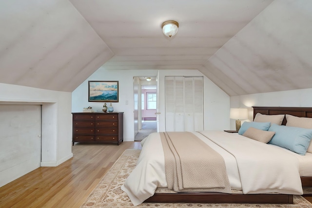 bedroom featuring baseboards, light wood finished floors, a closet, and vaulted ceiling