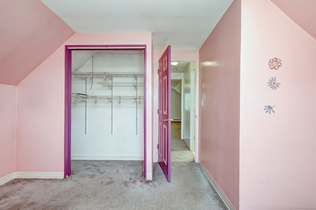 interior space with a closet, vaulted ceiling, baseboards, and carpet floors