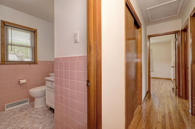 145 Russell Rd, Stratford, CT 06614 - hallway with a wainscoted wall, light wood-style floors, and tile walls