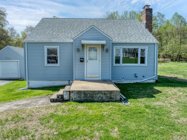 bungalow-style home featuring a garage, a front lawn, roof with shingles, a chimney, and an outbuilding
