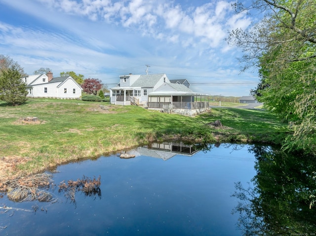 rear view of property featuring a yard, a water view, and a sunroom