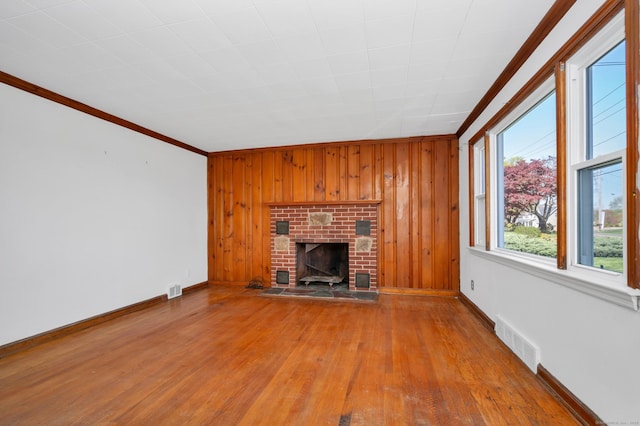 unfurnished living room featuring visible vents, ornamental molding, wood finished floors, a fireplace, and baseboards