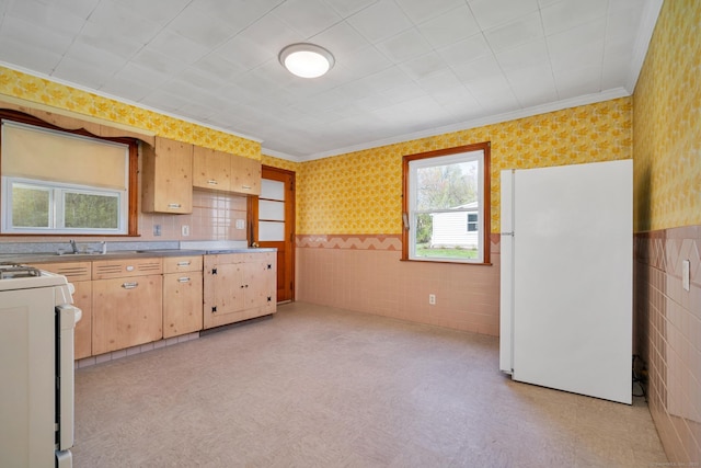 kitchen with gas stove, light countertops, freestanding refrigerator, wallpapered walls, and ornamental molding