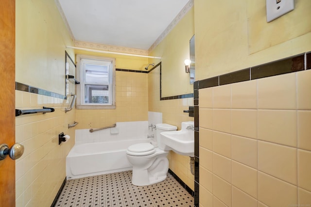 full bathroom with bathing tub / shower combination, toilet, tile walls, tile patterned floors, and a sink
