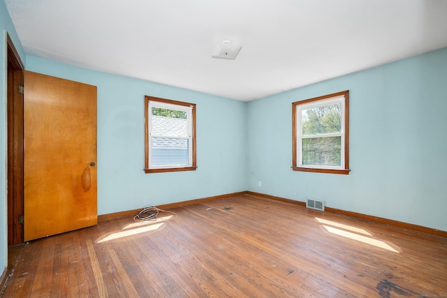 unfurnished room featuring baseboards, wood-type flooring, and visible vents