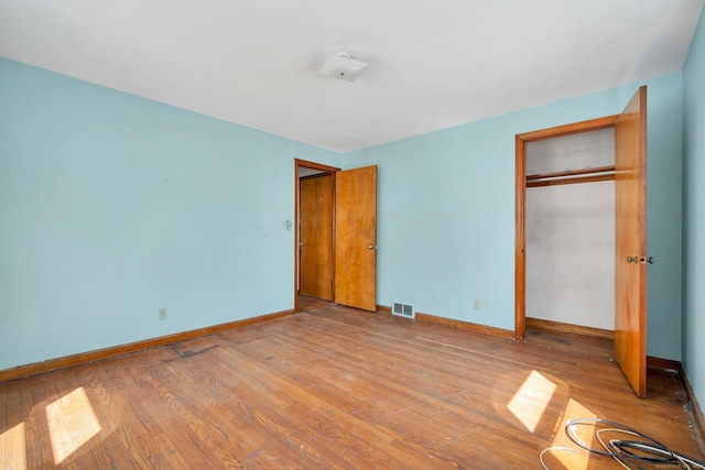 unfurnished bedroom featuring visible vents, baseboards, and wood finished floors