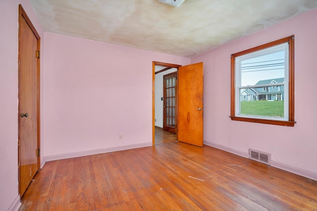 unfurnished bedroom with visible vents, light wood-style flooring, and baseboards