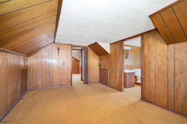 additional living space featuring wooden walls, vaulted ceiling, and carpet