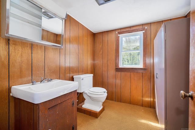 half bath with vanity, wood walls, and toilet