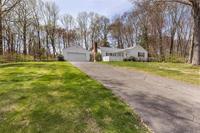 view of front of house with fence, a front yard, a chimney, an outbuilding, and a detached garage