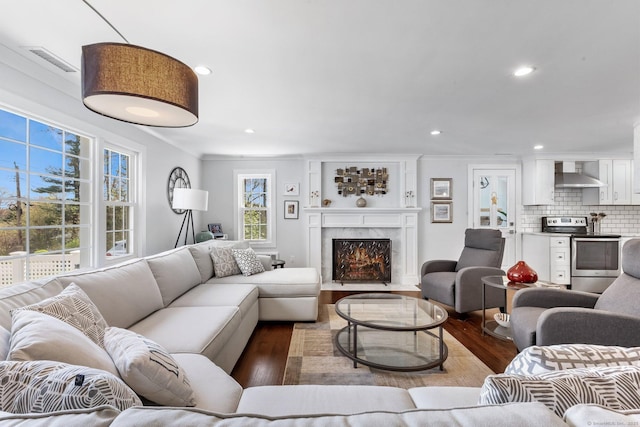 living room with a premium fireplace, recessed lighting, wood finished floors, and visible vents