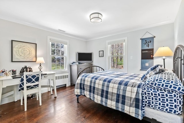 bedroom with crown molding, radiator heating unit, visible vents, and wood finished floors