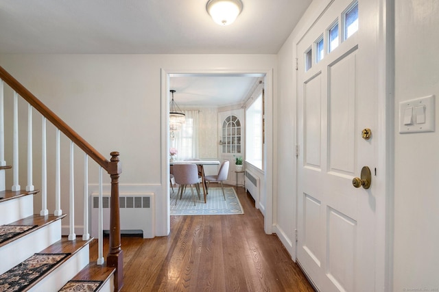 entrance foyer with stairs, radiator, wood finished floors, and a chandelier