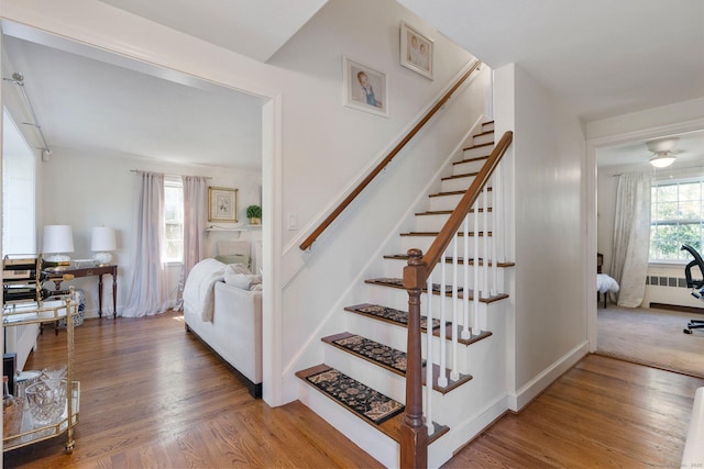 stairway with baseboards, radiator, and wood finished floors