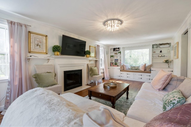 living room featuring crown molding, wood finished floors, a notable chandelier, and a fireplace