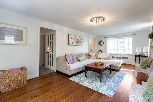 living room featuring crown molding, a notable chandelier, radiator heating unit, and wood finished floors