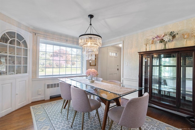 dining room featuring a chandelier, ornamental molding, radiator heating unit, and wood finished floors