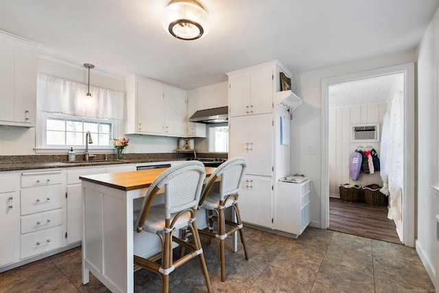 kitchen with wooden counters, a wall mounted air conditioner, white cabinetry, ventilation hood, and a sink