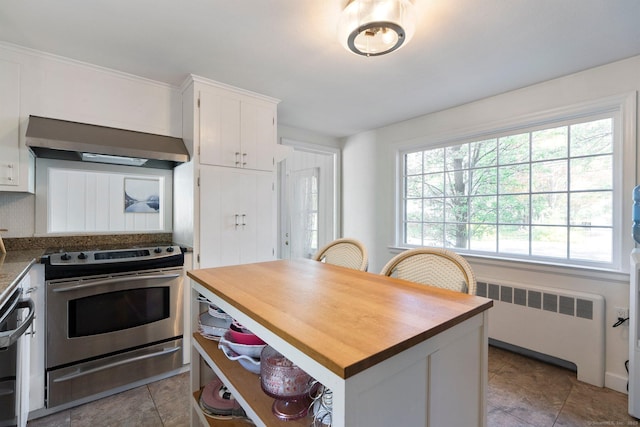 kitchen with butcher block countertops, radiator heating unit, white cabinetry, under cabinet range hood, and stainless steel electric range oven