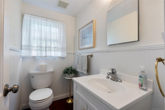 bathroom featuring visible vents, wainscoting, and toilet