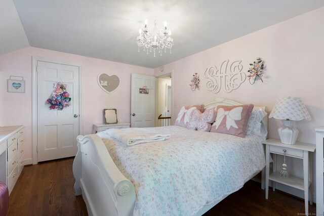 bedroom with dark wood finished floors, a chandelier, and vaulted ceiling