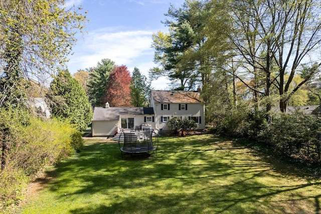 back of property featuring a lawn and a trampoline