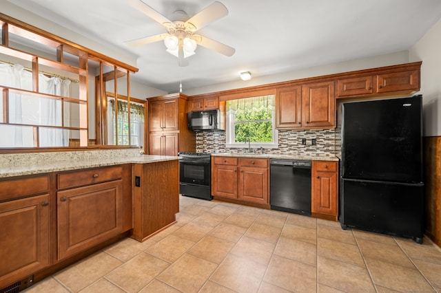 kitchen with decorative backsplash, brown cabinetry, ceiling fan, light stone countertops, and black appliances
