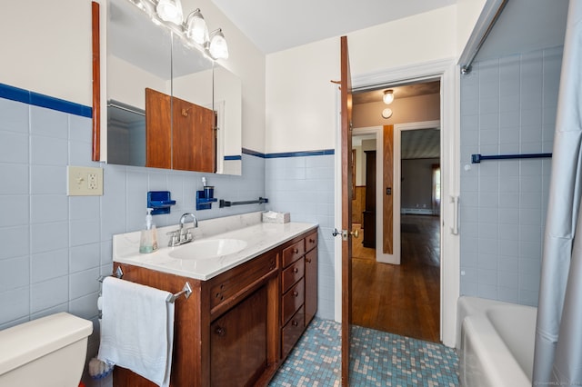bathroom featuring wainscoting, vanity, toilet, tile patterned floors, and tile walls