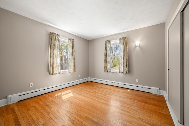 empty room with wood-type flooring, baseboards, and a baseboard heating unit