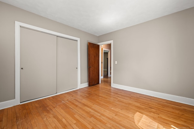 unfurnished bedroom featuring a closet, baseboards, and light wood-type flooring