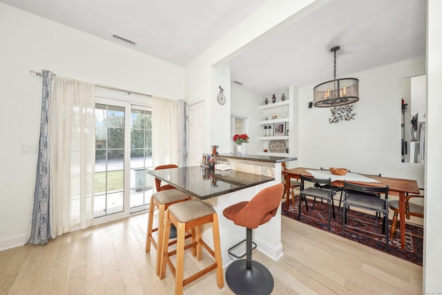 dining space with baseboards, visible vents, an inviting chandelier, and light wood-style floors