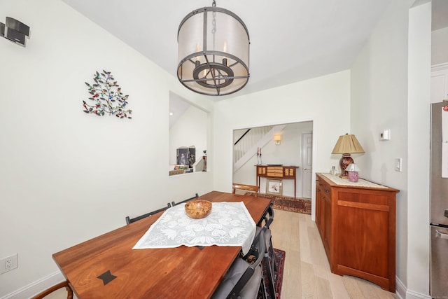 dining space with light wood-style floors, baseboards, and stairway