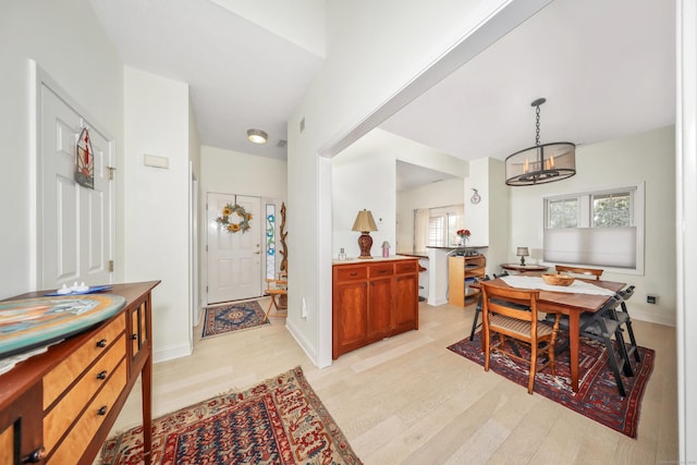 interior space with baseboards, a notable chandelier, and light wood-type flooring