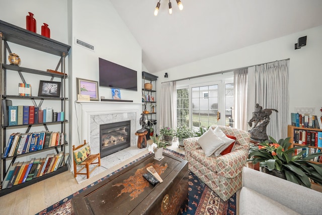 living area with visible vents, high vaulted ceiling, wood finished floors, and a fireplace