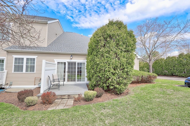 back of house with a lawn and a shingled roof
