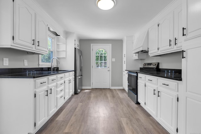 kitchen with premium range hood, white cabinets, a sink, light wood-style flooring, and stainless steel appliances