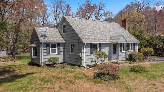 view of front of home featuring a shingled roof, a front yard, and a chimney