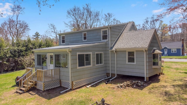 back of house with a lawn and roof with shingles