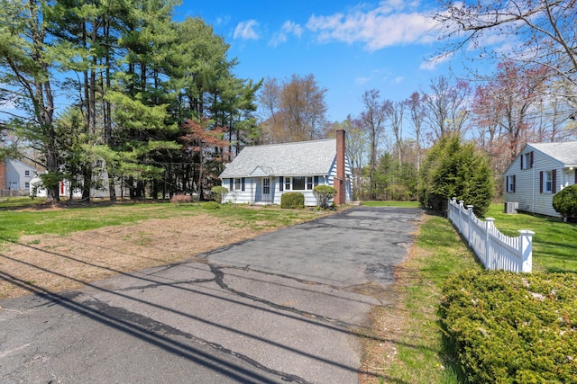 bungalow-style house with fence, a chimney, a front lawn, and aphalt driveway
