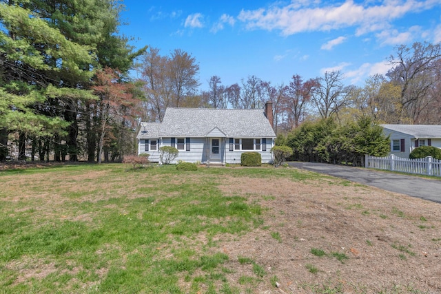 view of front facade with a front lawn, aphalt driveway, fence, and a chimney