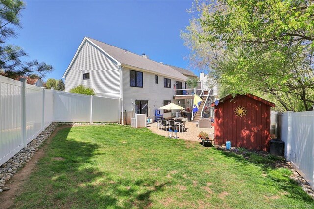 back of property with an outdoor structure, a patio, a fenced backyard, a lawn, and a storage shed