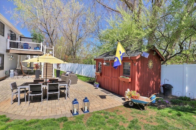 view of patio featuring an outdoor structure, outdoor dining space, a shed, and a fenced backyard